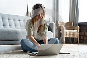 Just inspired. Confident young beautiful smiling woman working on laptop while sitting on the floor at home.