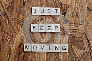 just keep moving text on wooden square, motivation quotes.