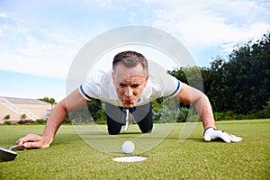 Just a little nudge. a handsome man trying to blow his golf ball into the hole. photo