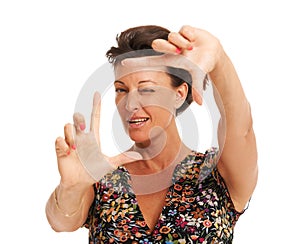 Just a little to your left, Perfect. Isolated mature woman closing one eye as she is planning how to photograph you -