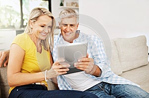 We just love a good read. a mature couple using a digital tablet while relaxing at home.