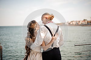 Just married boy and girl hugging each other on the pier on the lake