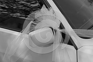 Just married car with a white bow on the driving mirror