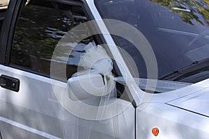 Just married car with a white bow on the driving mirror