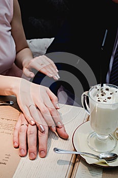 Just married couple hold hands and showing up wedding ring in cafe