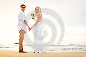 Just married couple holding hands on the beach