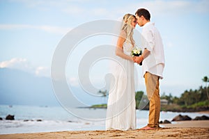 Just married couple holding hands on the beach at sunset