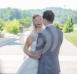 Just-married couple hugging each other and laughing in a park surrounded by hills and greenery
