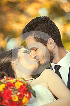 Just married couple kissing on blurred autumn background