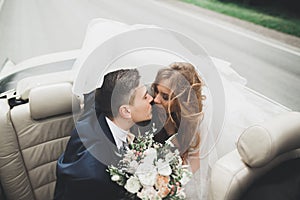 Just married couple in the luxury retro car on their wedding day