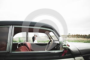 Just married couple in the luxury retro car on their wedding day