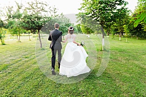 Just married couple running away in a green summer garden