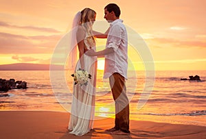 Just married couple on tropical beach at sunset