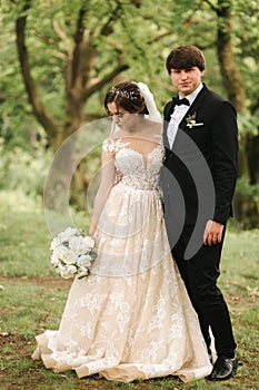 Just married coupleon green background, broom and bride walking in the forest