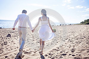 Just married happy couple running on a sandy beach