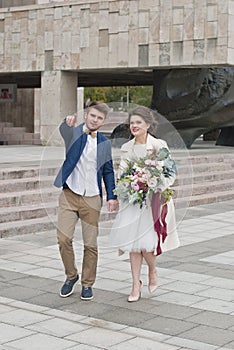 Just married loving couple in wedding dress and suit . Happy bride and groom walking running in the summer city.