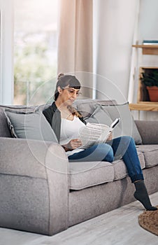 Just me, myself and a good book. Full length shot of an attractive young woman sitting alone in her living room and