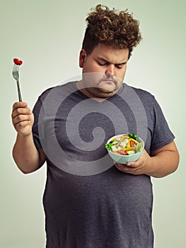 This is just not going to happen. Studio shot of an overweight man holding a bowl of salad.