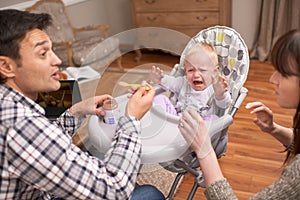 Just one more bite, my little angel. A young father feeding his daughter some baby food.