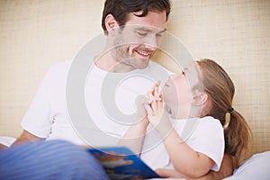 Just one more story... PLEASE. A devoted father reading his young daughter a bedtime story.