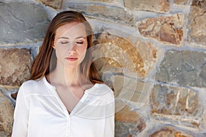 Just taking a moment to relax. a young woman standing outdoors with her eyes closed.