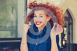 Just won an apartment!!! Super excited Smiling red head curly girl holding showing keys to her new home isolated near apartment