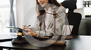 justice and law concept.law theme wooden desk, books, balance. Male judge in a courtroom the gavel,working with digital tablet