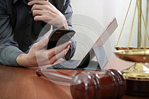 justice and law concept.Male lawyer in office with the gavel,working with smart phone and digital tablet computer and brass scale