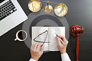 justice and law concept.Top view of Male judge hand in a courtroom with the gavel and brass scale and computer and open bible boo