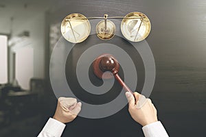 justice and law concept.Top view of Male judge hand in a courtroom with the gavel and brass scale on dark wood table