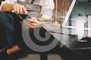 Justice and Law context.Male lawyer hand sitting on sofa and working with smart phone,digital tablet computer docking keyboard wi