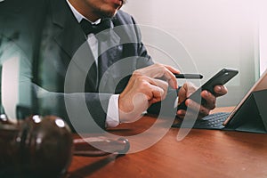 Justice and Law context.Male lawyer hand working with smart phone,digital tablet computer docking keyboard with gavel and