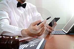 Justice and Law context.Male lawyer hand working with smart phone,digital tablet computer docking keyboard with gavel and