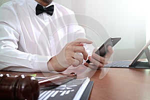 Justice and Law context.Male lawyer hand working with smart phone,digital tablet computer docking keyboard with gavel and