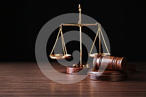 Justice scales and judges gavel on table against black background