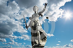 Justitia symbol of justice in front of background with sky and c