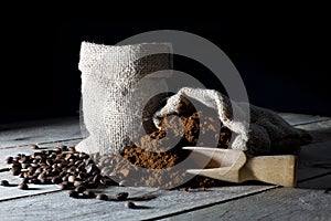 Jute Bags Filled with Ground Coffee and Coffee Beans on an Old Rustic Wooden Table on Black