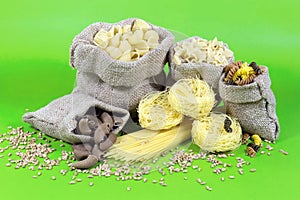 Jute Bags Filled with Pasta of Different Colors and Shapes On Green Background