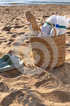 Jute beach bag and flip flops on the sand. Summer vacation lifestyle concept.