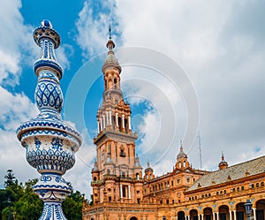 Juxtaposition of blue and white ceramic azulejo tiles against one of the baroque sandstone tower at Plaza de Espana in Seville, Sp