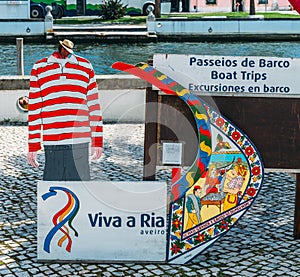 Juxtaposition of facade of traditional moliceiro boat and gondolier next to a charming canal