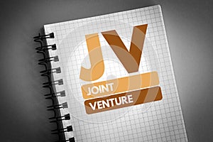 JV - Joint Venture acronym on notepad, business concept background