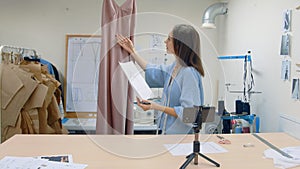 4K Young woman working in a clothing store. The designer shoots his work on the phone camera