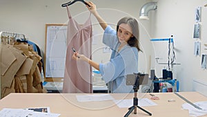 4K Young woman working in a clothing store. The designer shoots his work on the phone camera