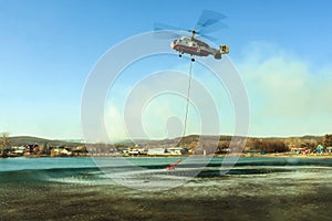 A KA-32 helicopter of the Ministry of Emergency Situations hovering over a lake from which water is drawn to extinguish