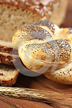 Kaiser bread roll with ear of rye on wooden table