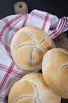 The Kaiser bread rolls. A crusty round bread rolls on a linen kitchen cloth and a wooden cutting board