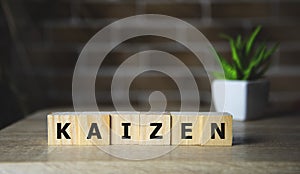 Kaizen improvement sign made of blocks on a wooden desk in a bright room