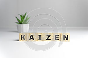 Kaizen improvement sign made of blocks on a wooden desk in a bright room