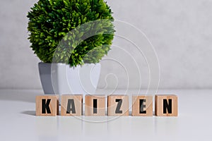 Kaizen improvement sign made of blocks on a wooden desk in a bright room